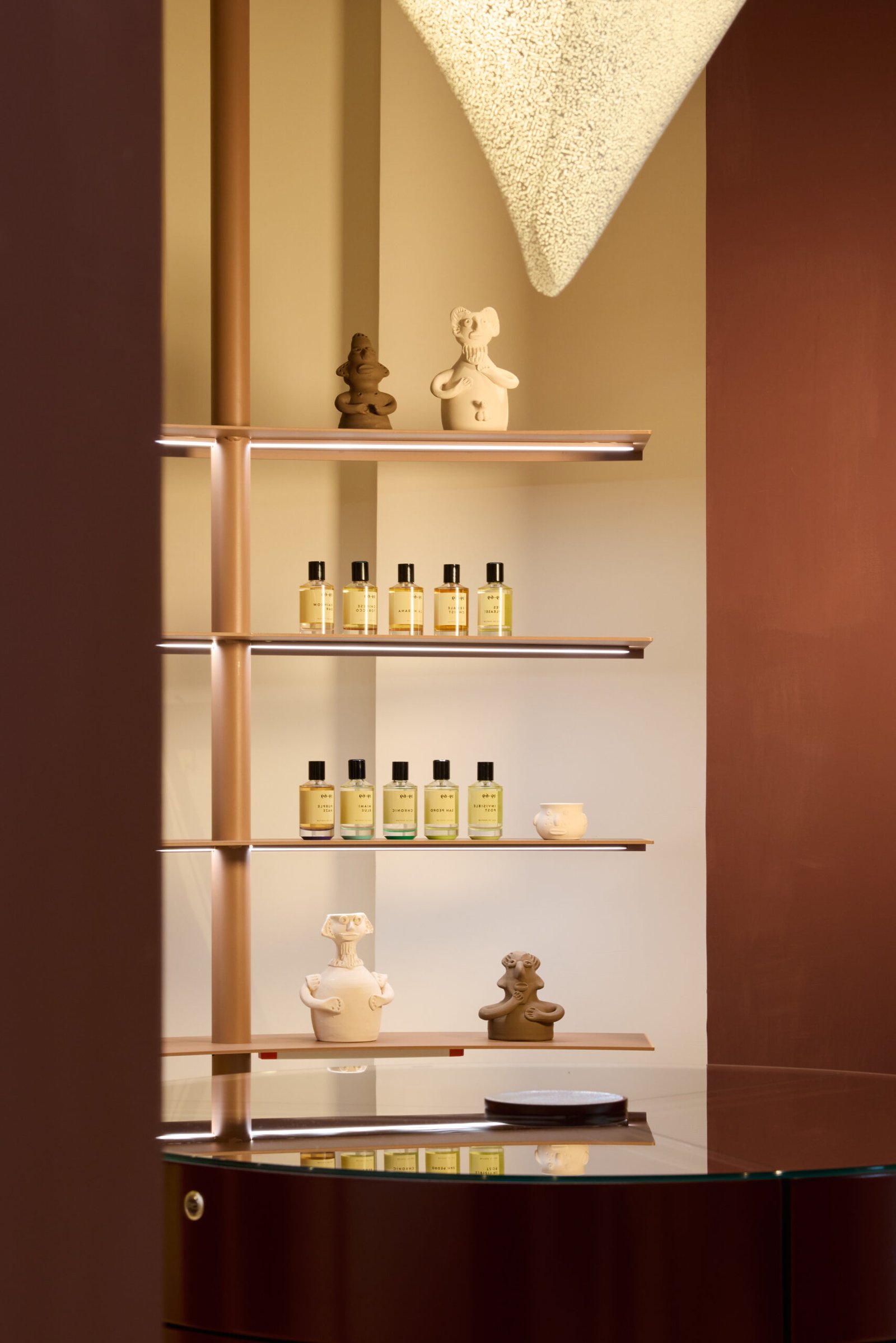 Estante con botellas de productos de belleza amarillas y figuras decorativas en el fondo
